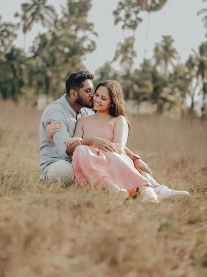 A romantic portrait of the couple sitting in a field of tall grass, adding a different texture and feel to their coastal pre-wedding shoot.