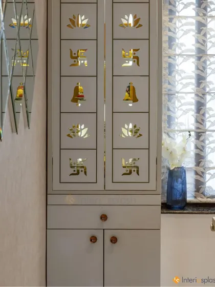 A beautiful puja unit with custom-designed doors featuring sacred symbols like the swastika, lotus, and bell. The design is both traditional and elegant.