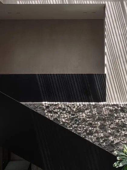 A detail of the architectural play of light and shadow against a textured stone wall. This is a core concept of the GAIA house, where natural elements create ever-changing art.