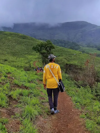 A lone trekker walks along a path in Kudremukh National Park, showcasing the vastness and solitude one can find on our trips.