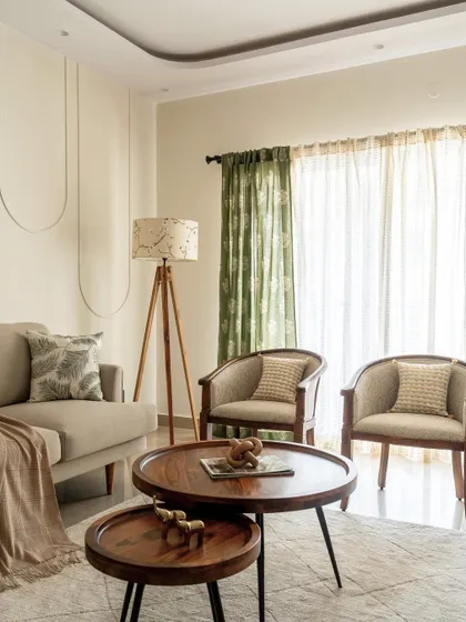 This elegant living room blends traditional and modern furniture. I used vibrant green curtains and a tripod floor lamp to add pops of color and character against a neutral backdrop with subtle wall molding.
