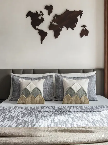 For the travel lover, this bedroom features a wooden world map as wall art. The look is grounded with earthy, textured pillows and a patterned bedspread, creating a space that inspires adventure.