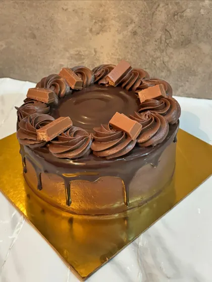 A simple chocolate drip cake topped with KitKat pieces, perfect for a casual birthday celebration.