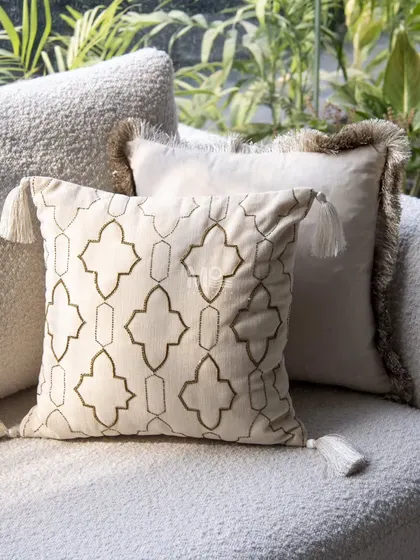 A cushion featuring a timeless trellis pattern with delicate gold embroidery and corner tassels. This piece adds a touch of luxury and is perfect for bringing an earthy, elegant vibe indoors.