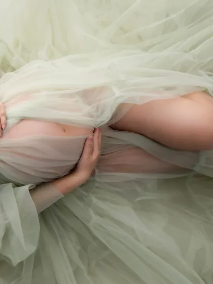 A close-up detail shot focusing on the hands cradling the baby bump. These are the little moments, the gentle touches, that tell the biggest stories.