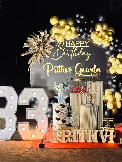 An outdoor surprise party for a 33rd birthday. This setup includes a custom backdrop, black and gold balloons, and large marquee numbers, complete with sparklers for a dramatic reveal.