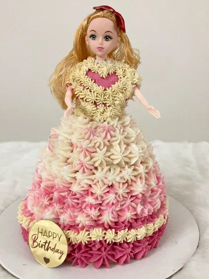 A dreamy Barbie doll cake where the cake itself forms her beautiful floral gown. The dress is meticulously piped with pink and white buttercream rosettes.