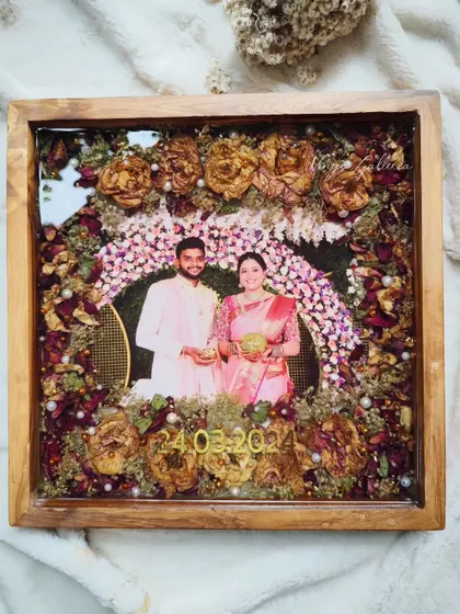 A full view of a stunning 14x14 inch teakwood frame, preserving a couple's varmala flowers around their wedding photo.