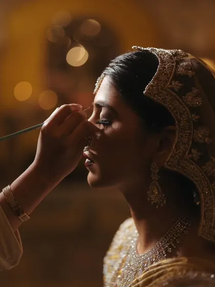 A dramatic shot of the bride getting her final makeup touches, with beautiful lighting highlighting her features.