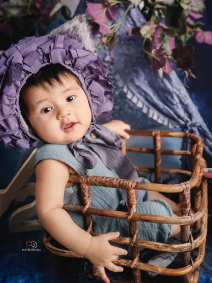 Celebrating the half-birthday milestone at six months old. This happy baby sits in a wicker basket with a '1/2' sign, showing off a huge, infectious giggle.