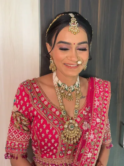 A joyful, eyes-closed smile. The soft purple and pink eyeshadow adds a touch of modern romance to her traditional Gujarati bridal look.