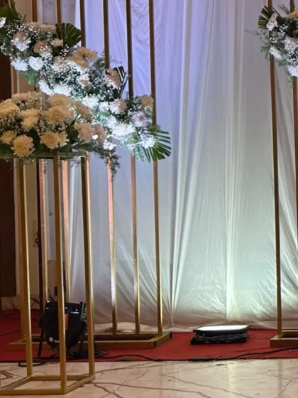 Minimalist and modern decor featuring tall, slender golden stands with simple white floral arrangements, perfect for an elegant and understated event.