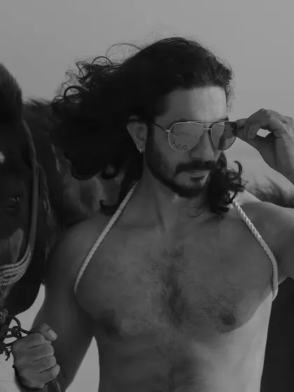 A series of black and white images from a male editorial shoot on the beach with a horse. The monochrome style gives these photos a classic, timeless, and heroic quality.