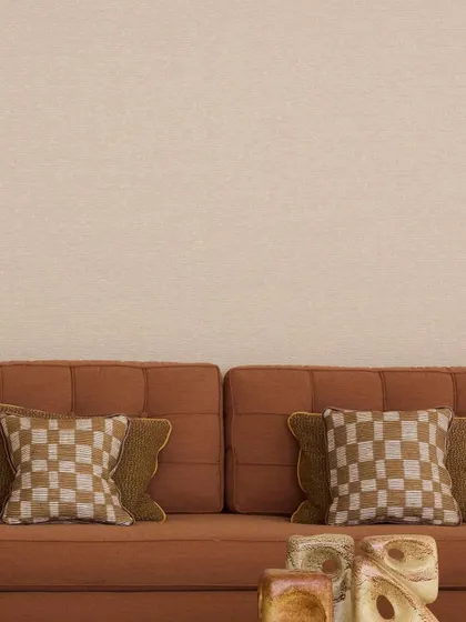 The 'Saint-Honoré' sofa by Nobilis, upholstered in 'Cima', an indoor/outdoor satin that mirrors the elegance of combed wool. The checkered cushions add a touch of graphic interest to the refined, rust-colored sofa.