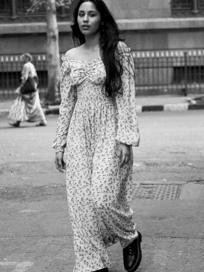 A full-length shot of the model walking down a quiet street. The black and white gives it a classic, almost nostalgic feel.