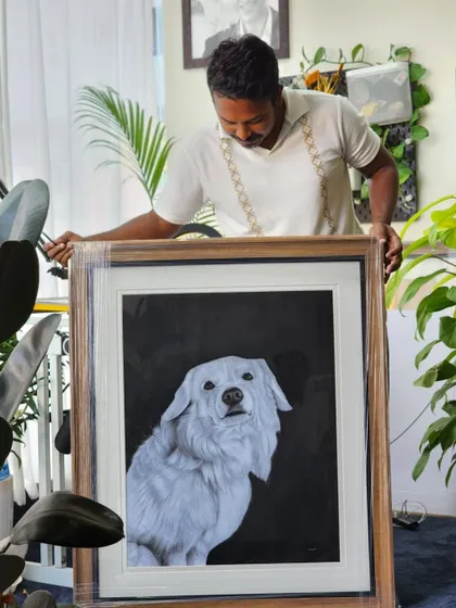Holding up the large, framed dog portrait. It's incredibly rewarding to see the final piece come together.