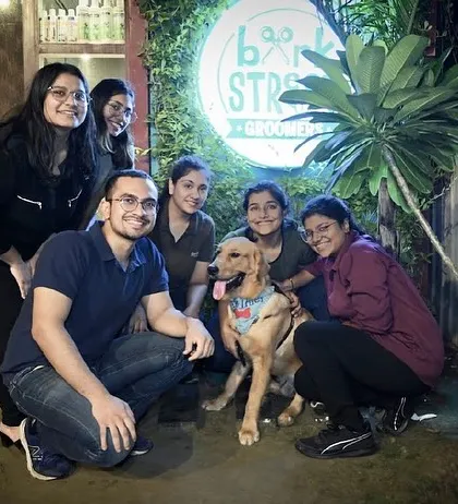 A group of friends posing with a happy doggo right by our outdoor sign. It's the perfect spot for a group photo.