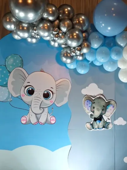 A detail shot of a baby elephant backdrop, showing the cute characters and the blue and silver balloon garland.