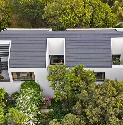 The house is designed with deep-set windows and recessed balconies, creating a play of light and shadow on the facade while providing shade and privacy for the rooms within.