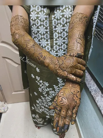 A complete look at bride Daniya's henna, including the custom initial "S" worked into the palm design.