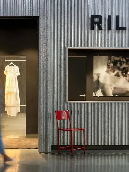 The entrance to the Rilievo fashion showroom, where industrial corrugated walls meet high fashion. A single red chair adds a pop of color, hinting at the creative and edgy design that lies within this 1,200 sq. ft. space.