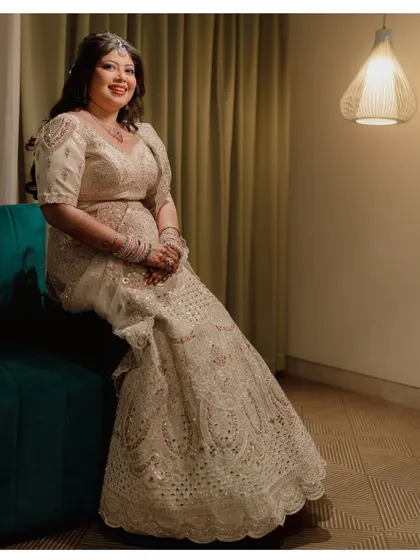 A full-length portrait of the bride, Navya, seated elegantly in her beautiful reception lehenga.