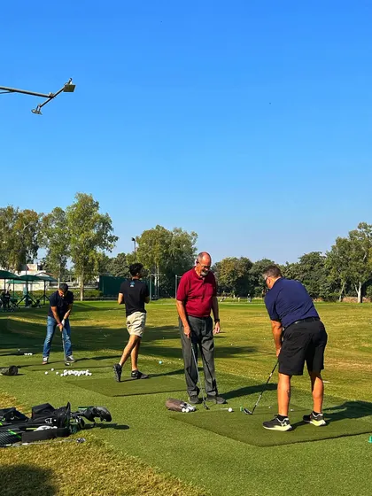 A coach gives a tip to a player on the range, showing the informal instruction available.