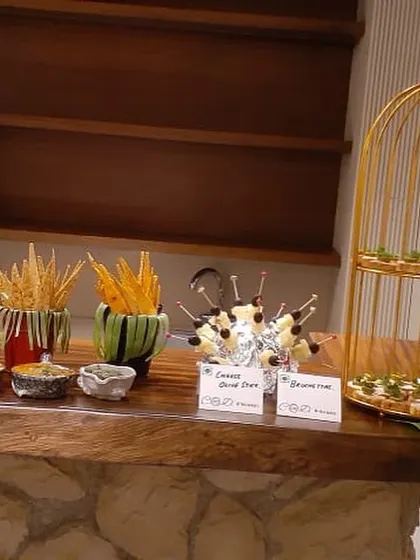 A stationary appetizer bar featuring cheese and olive skewers, bruschetta, and various crisps with dips. This provides a self-service option for guests to graze at their leisure.