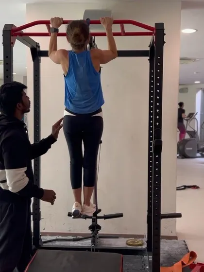 Spotting my client to ensure she maintains proper form and safety during her pull-up training.