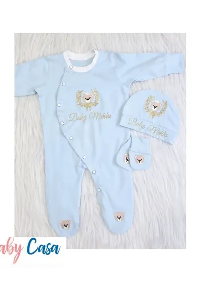 A closer look at the matching romper, cap, and mittens for the "Baby Mehta" set. The light blue fabric is embroidered with a golden lion crest for a touch of elegance.