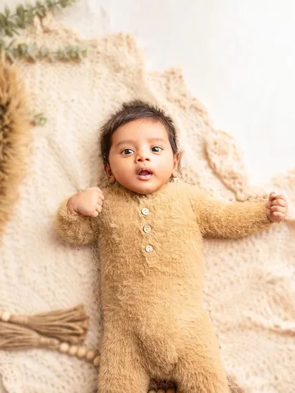 Another angle of our little teddy bear, looking so alert and curious. The simple, textured background keeps the focus entirely on the newborn.