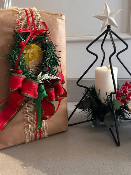 This gift wrap features a charming mini wreath as the centerpiece. It's a creative alternative to a traditional bow and adds a lovely, handmade touch to your Christmas presents.