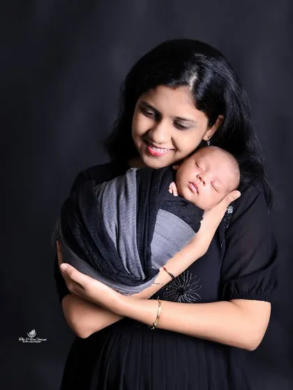 A mother's loving gaze at her newborn baby. We capture these quiet, intimate moments against a simple black background to emphasize the emotional connection.
