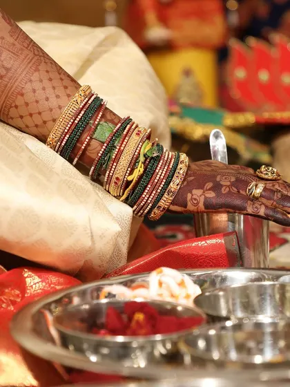 A close-up of the bride's hand during a wedding ritual, showing the intricate details of the stain.