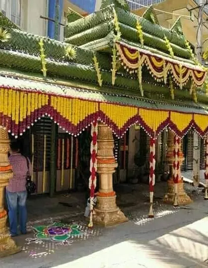 A large step chapra built for a grand ceremony. The structure is supported by decorative pillars and adorned with yellow and red flower garlands.