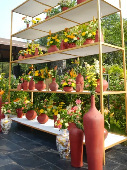 A modern shelving unit used as a decor piece, filled with terracotta vases and colorful floral arrangements, adding height and interest to the space.