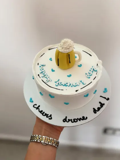 A fun Father's Day cake with a "cheers dad" message and an edible beer mug on top.