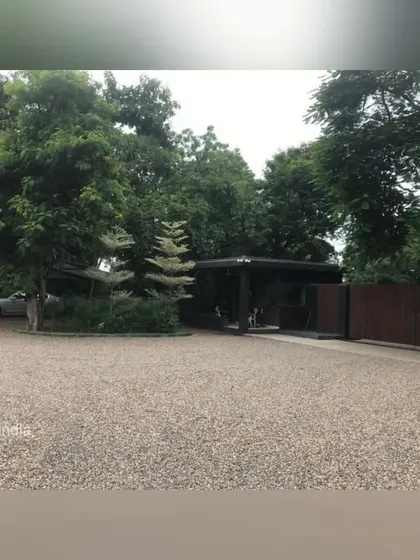 The entrance gate and parking area are softened by a grove of mature trees and dense shrubbery. This approach to driveway landscaping helps integrate the functional aspects of a property into a cohesive, green environment.