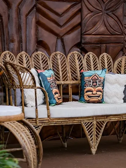 A duplicate of image 214, showing the stylish cane sofa and carved wooden backdrop.