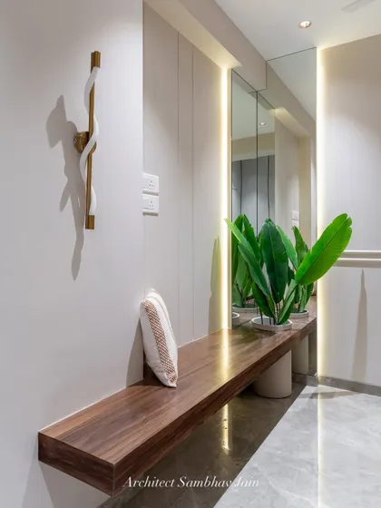 A serene corner designed to unwind. This wooden veneer shelf doubles as a seat or daybed, seamlessly extending into a tall, inbuilt planter box. The L-shaped mirror reflects the lush greens and expands the visual depth of the space.