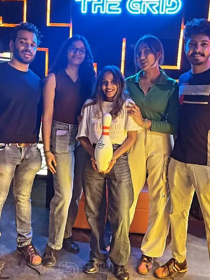 A group of friends posing with a bowling pin. Not sure what's more impressive, their scores or their poses.