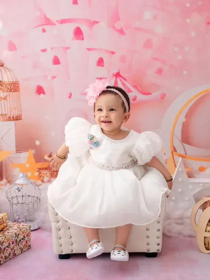 In a magical pink castle setting, this little girl celebrates turning one, looking like a true princess in her white dress.
