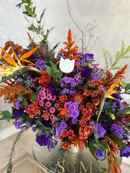 For the lover of bold, bright, and exotic. This is a symphony of deep pinks and dramatic oranges, interspersed with sprays of purple and the delicate softness of greens.