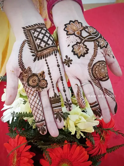 An example of Arabic and Indian fusion mehndi style. One hand has a modern, spaced-out pattern with lotuses, while the other features a more traditional design with jaali work.