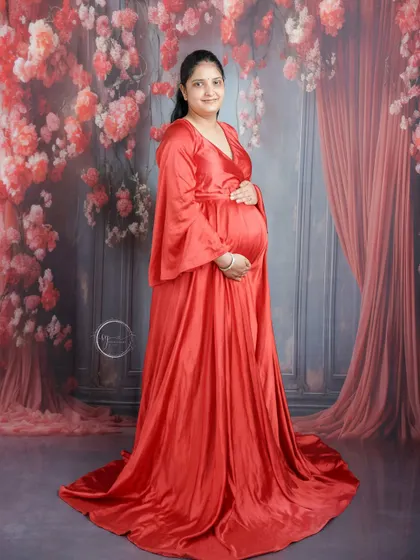 A beautiful full-length portrait of the mom-to-be in a striking red gown. The elegant draping of the fabric and the soft lighting create a timeless look.