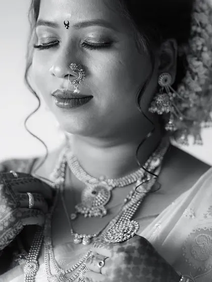 A classic monochrome portrait of a bride. The black and white tones emphasize the rich textures of her jewelry and the serene emotion on her face.