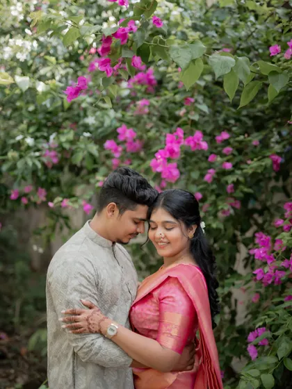 A romantic portrait of the couple embracing in front of a wall of vibrant pink bougainvillea flowers.