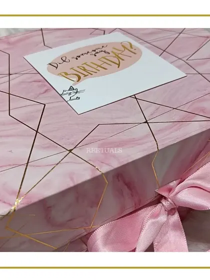 The elegant pink marble-patterned gift box, tied with a satin ribbon.