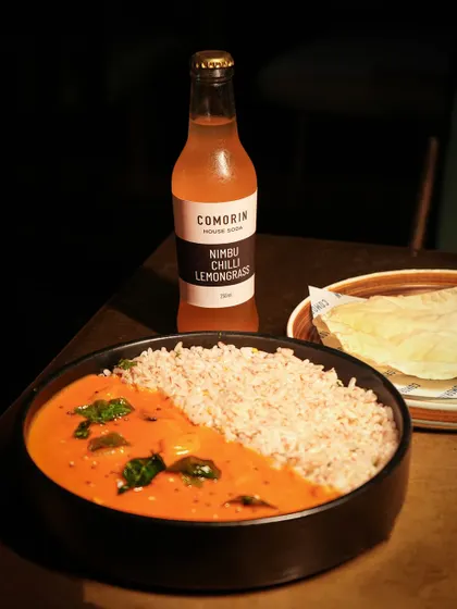 A bowl of my Kerala-style Meen Curry, served with traditional red rice and a crisp papad. It's spicy, tangy, and full of the warmth of home.
