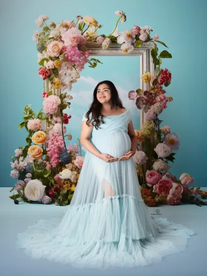 A dreamy, sky-blue portrait that feels like a painting. The floral frame and ethereal gown come together to create a truly artistic and beautiful maternity photo in the studio.